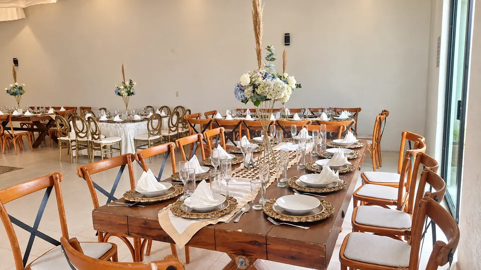 Mesa de boda de madera con vajilla y centro floral azul y blanco.