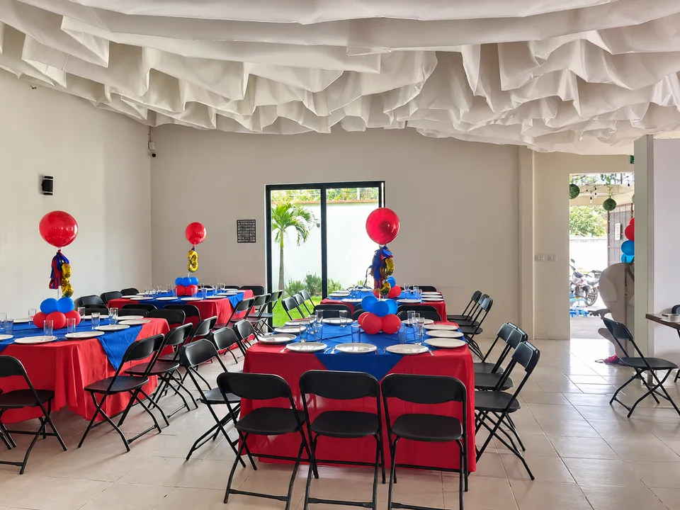 Vista del salón con mesas rojas y azules para cumpleaños infantil.