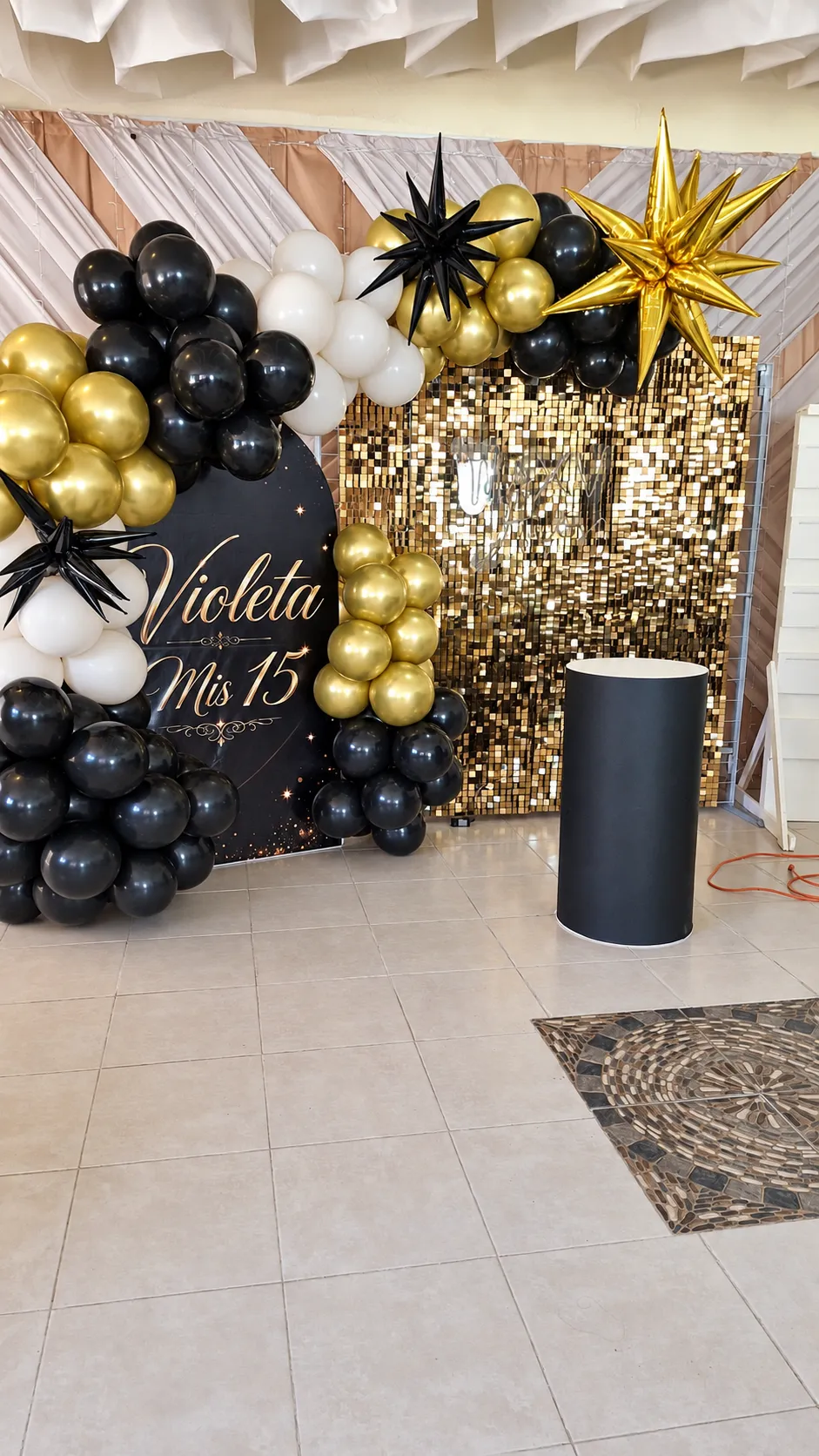 Backdrop negro y dorado para XV años con estrellas y globos.