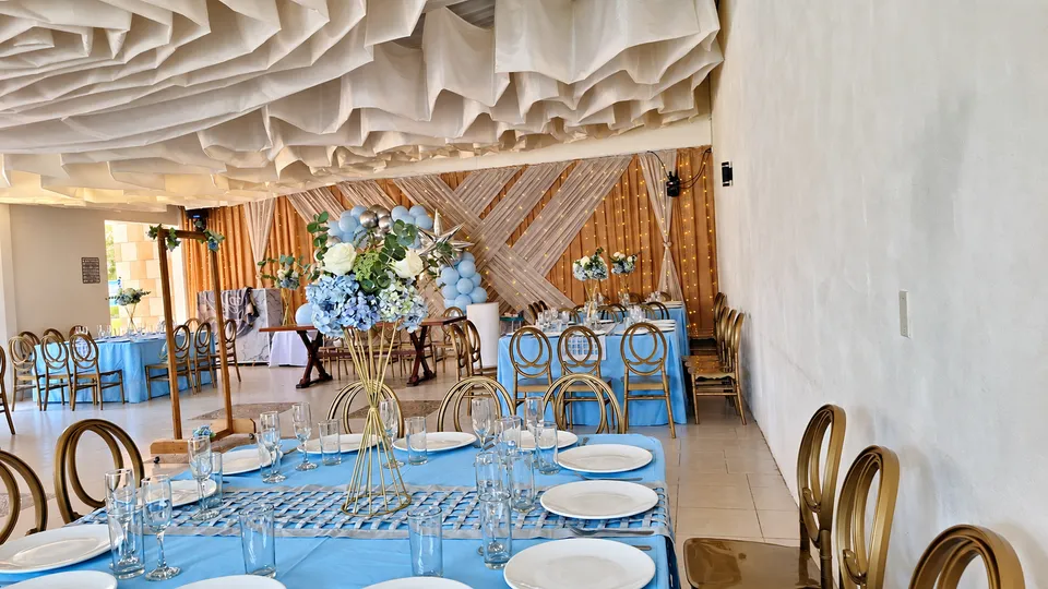Salón montado en azul con centros florales y decoración de XV años.